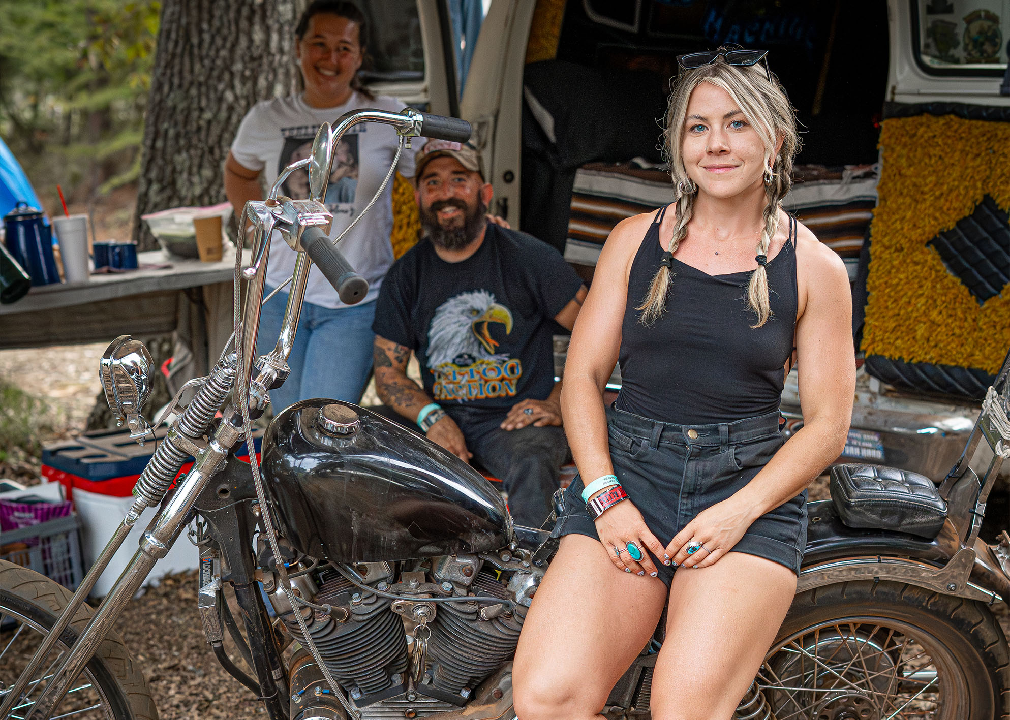 Two women and a man pose with a black bike