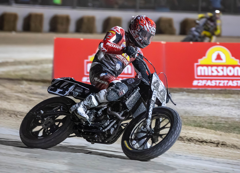 Brandon Robinson rides motorcycle #44 through a dirt-track corner under the lights during a flat track race
