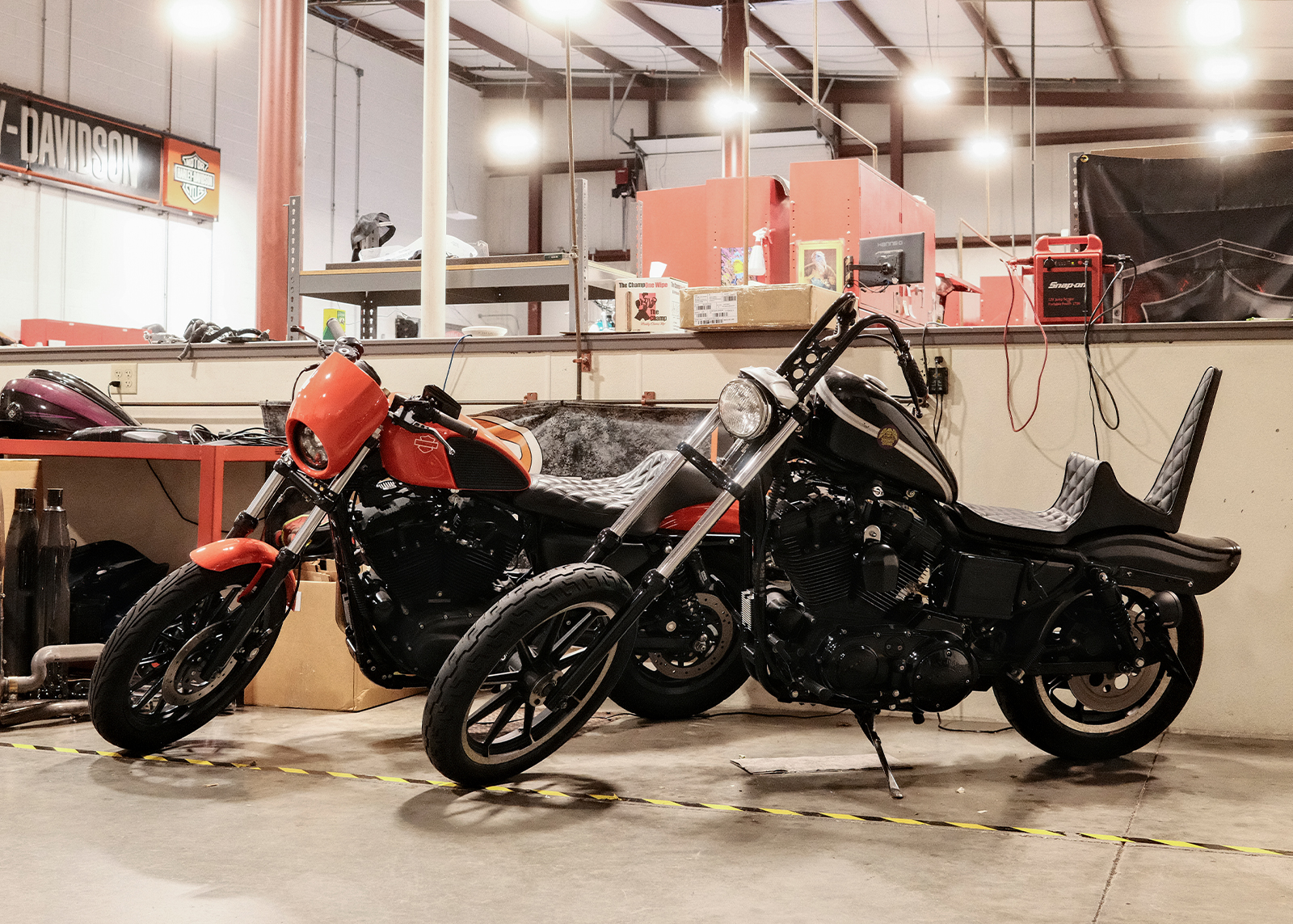 Two custom Harley-Davidson motorcycles, one red and one black, parked inside the Classic Harley-Davidson service area.