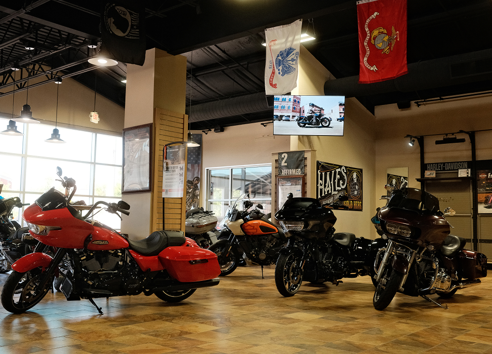 Man O’ War Harley-Davidson showroom floor featuring touring motorcycles, military flags, and dealership displays