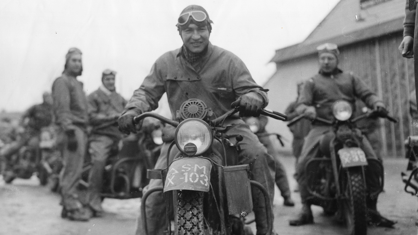 A soldier smiles while riding a Harley-Davidson
