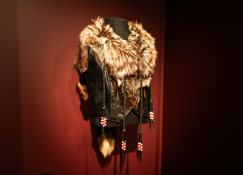 Gail Anderson’s one-off vest lined with fox pelt displayed on a stand, featuring hanging ties, and decorative bead accents