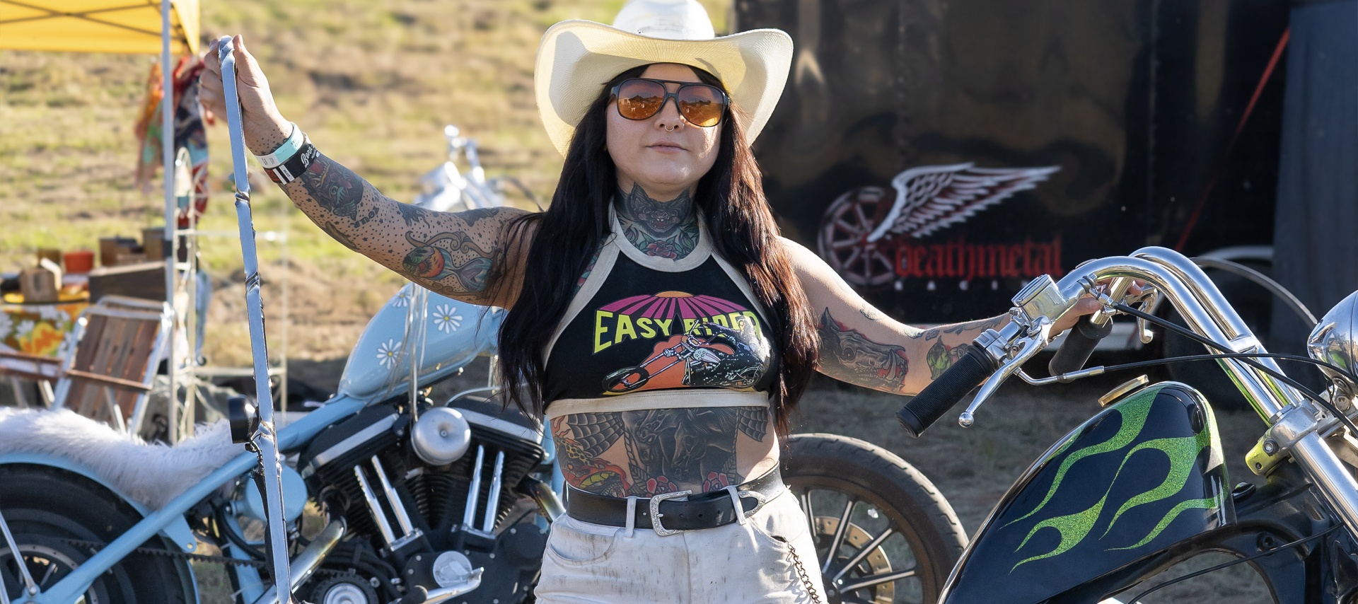 Woman in cowboy hat posing with a Harley, landscape