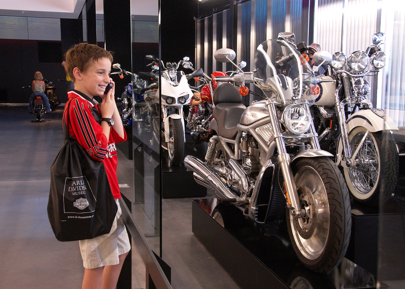 Visitante com sacola de compras olhando uma fileira de motocicletas HD