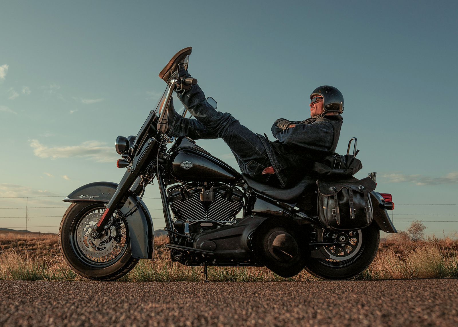 A rider parked on the side of the road kicks back with his feet rested on the handlebar on the way to Sturgis, South Dakota.