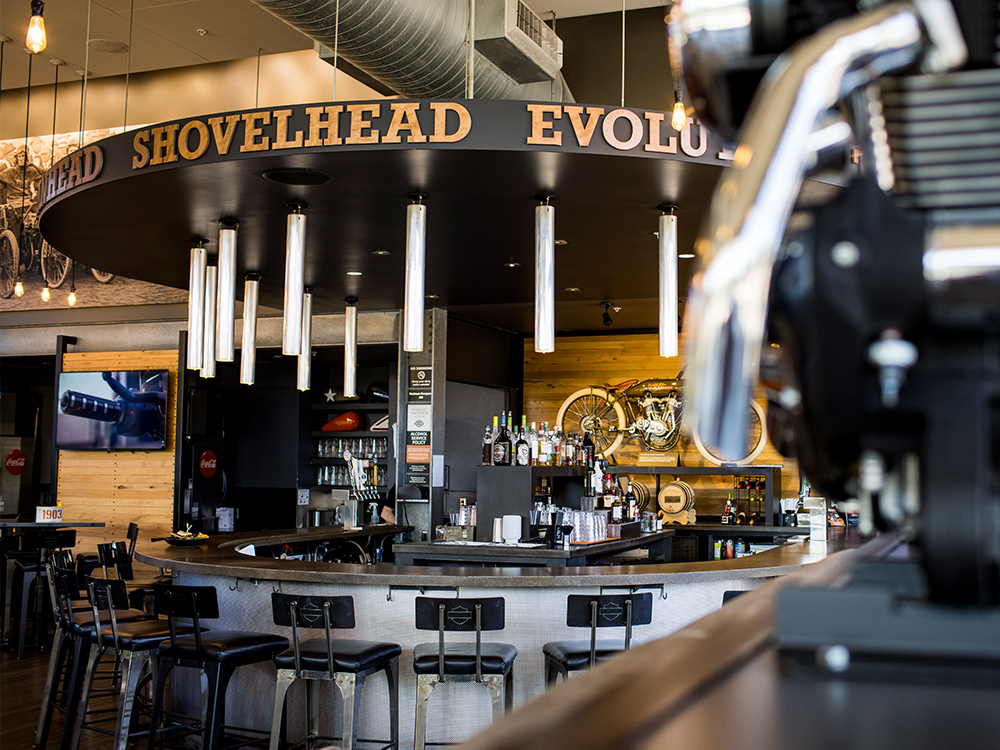 Harley-Davidson themed bar interior with circular counter, bar stools, and hanging lights