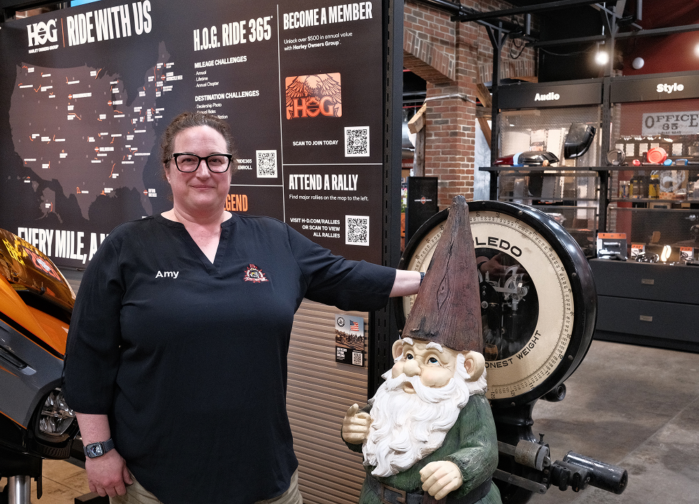 Harley-Davidson staff member standing beside vintage scale and display in dealership retail space