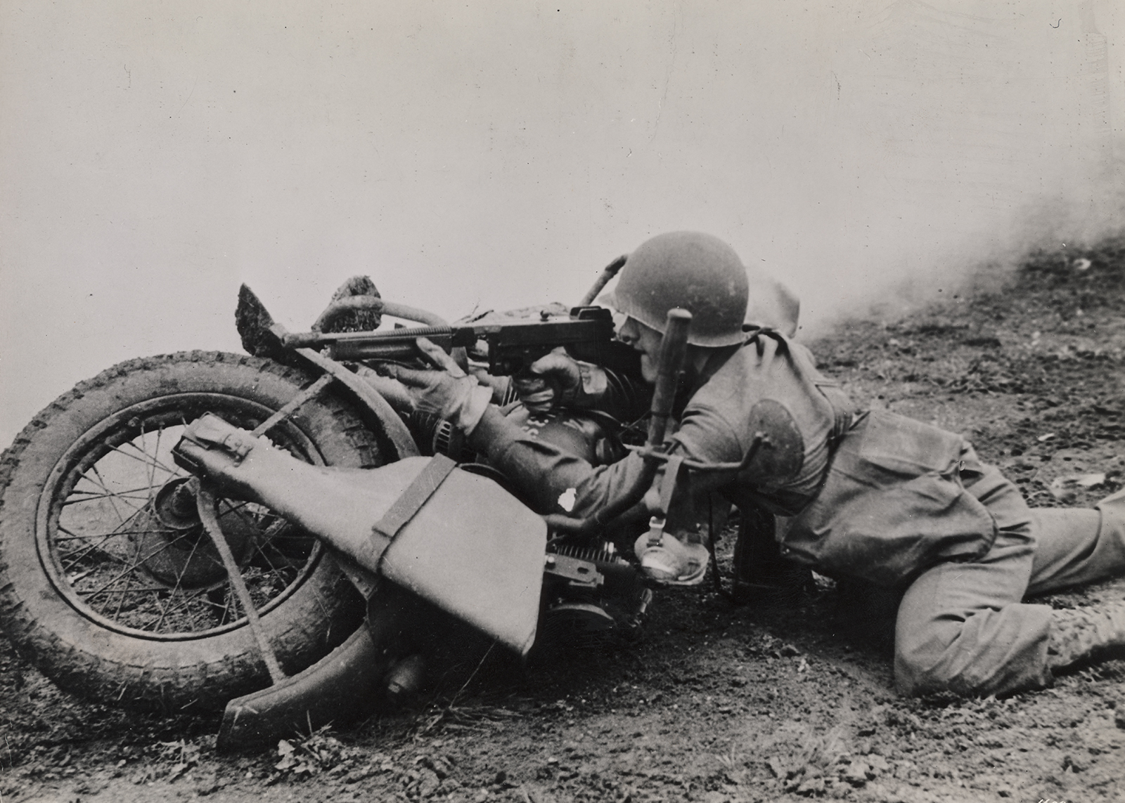 Soldier uses his motorcycle as a barrier to prop his rifle on 