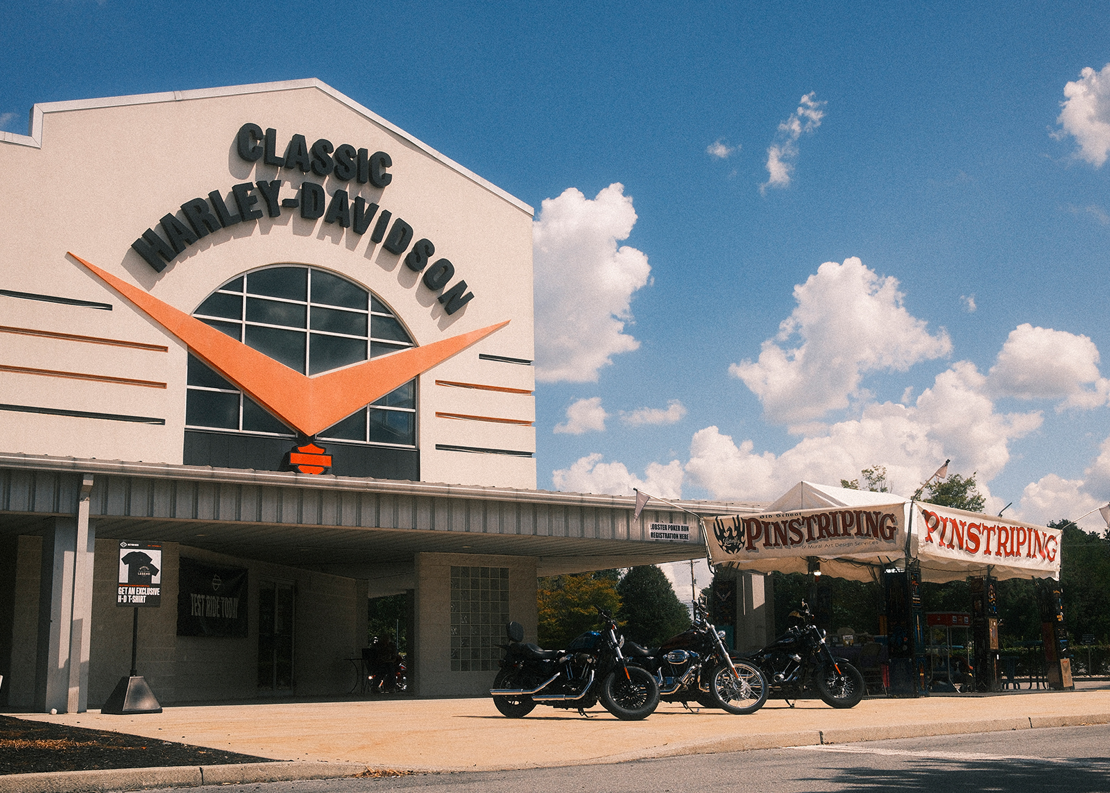 Exterior of Classic Harley-Davidson in, with motorcycles parked and a pinstriping tent outside.