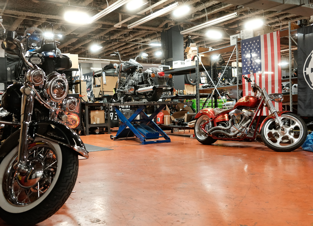 Man O’ War Harley-Davidson service department with motorcycles on lifts, workstations, and an American flag
