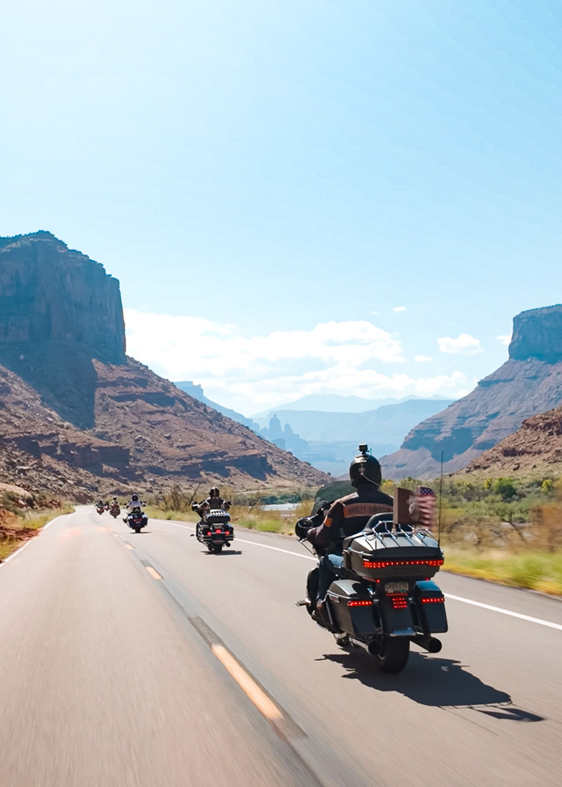 A line of motorcycles rides through a rocky valley
