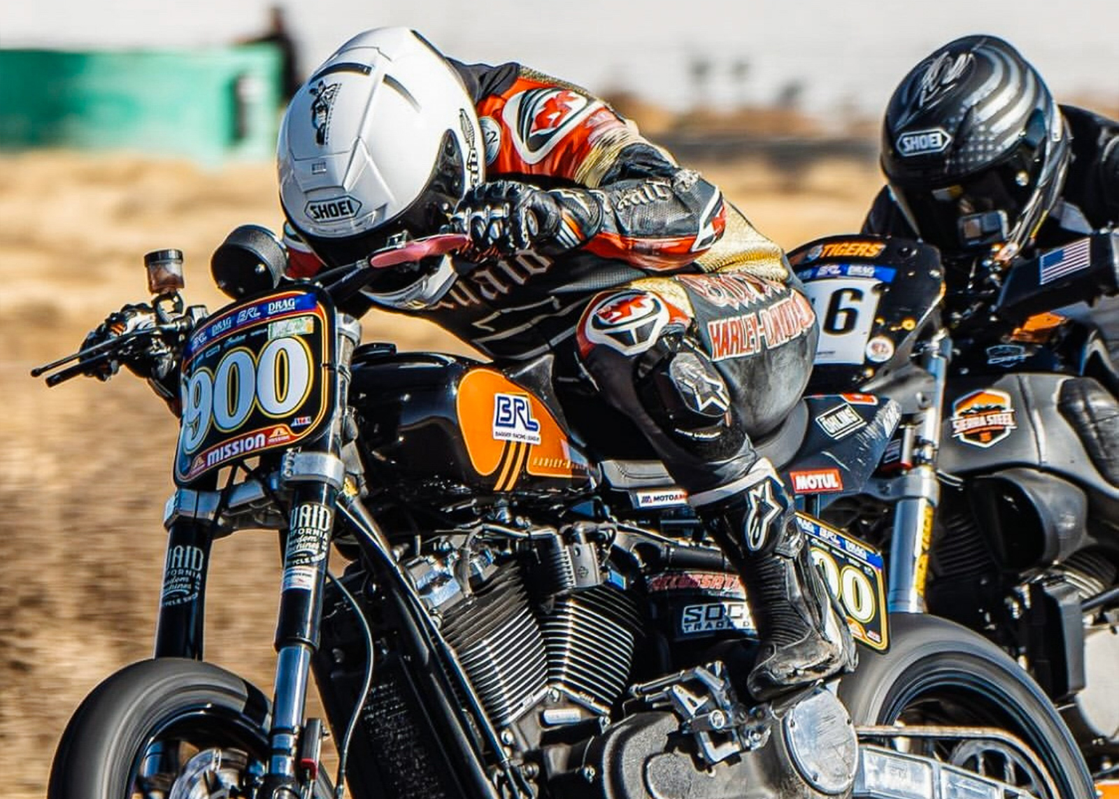 A close up of two riders racing motorcycles on a track.