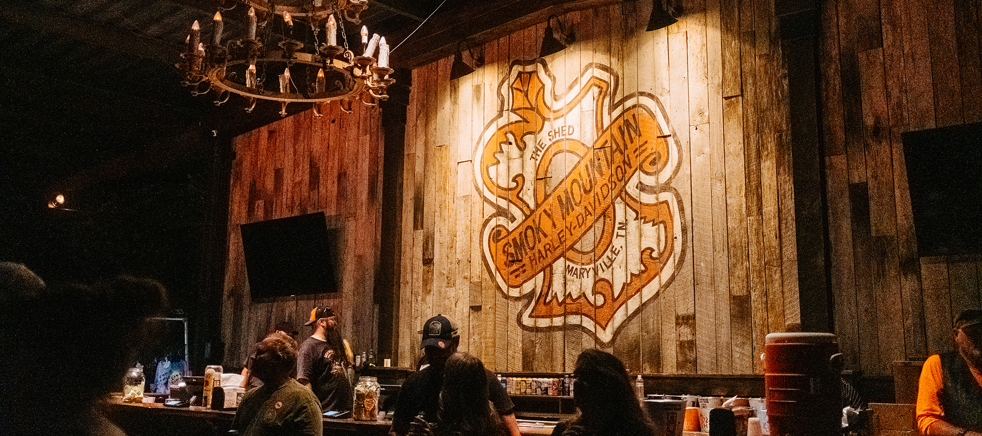 A Smoky Mountain Harley-Davidson motif is painted on rustic wood in the dimly lit Shed BBQ.