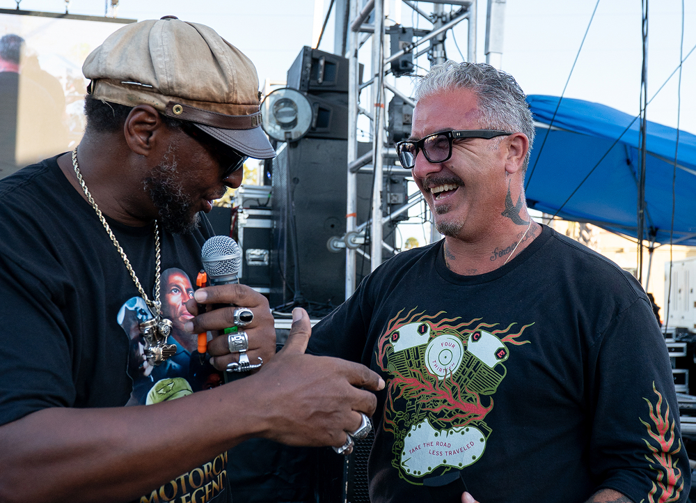 Randy “Detroit” Hayward reaches to shake hands with a smiling bike builder as he awards a DAM ring on stage