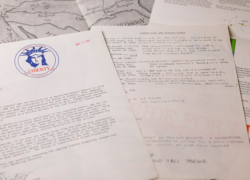 Typed letters and handwritten notes with Harley-Davidson Liberty Centennial letterhead spread on a desk