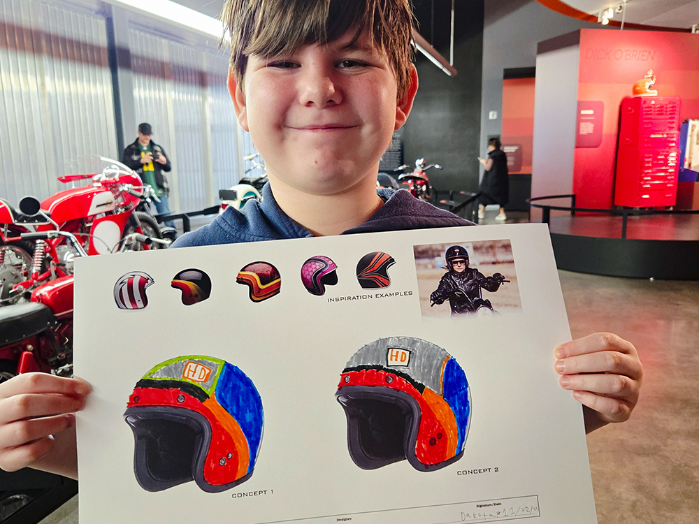 Child holding custom helmet design artwork in museum exhibit
