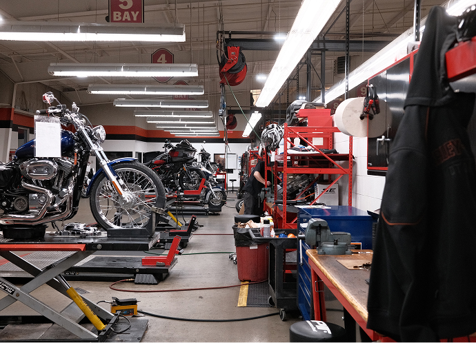 The Harley‑Davidson of Madison service bay with motorcycles on lifts, tools and workstations arranged under bright shop lighting