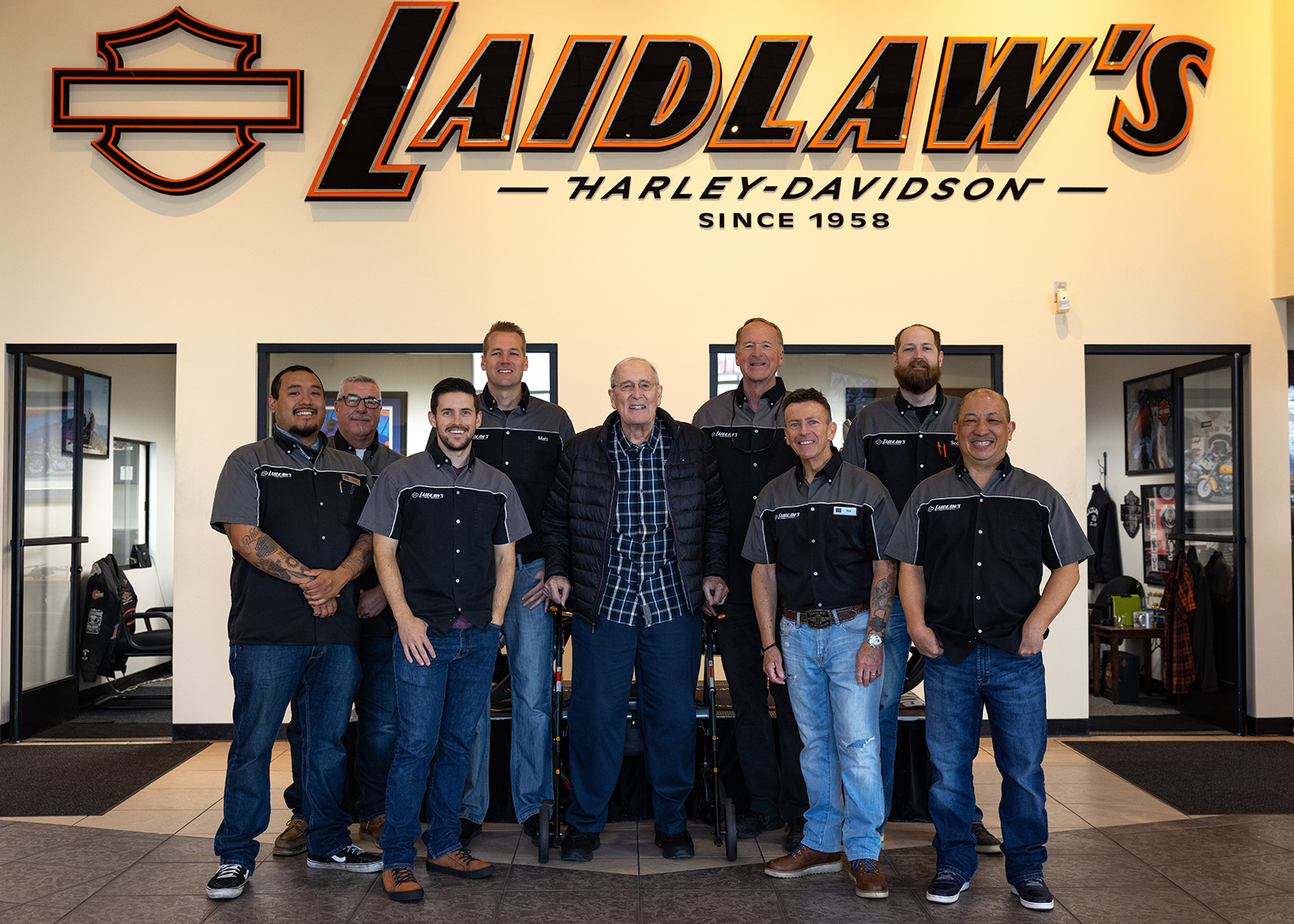 The Laidlaw’s Harley-Davidson staff poses in front of a big, wall-mounted Laidlaw’s sign.