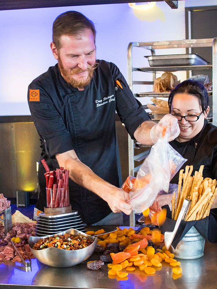 Chef preparing charcuterie display with meat sticks and cheese