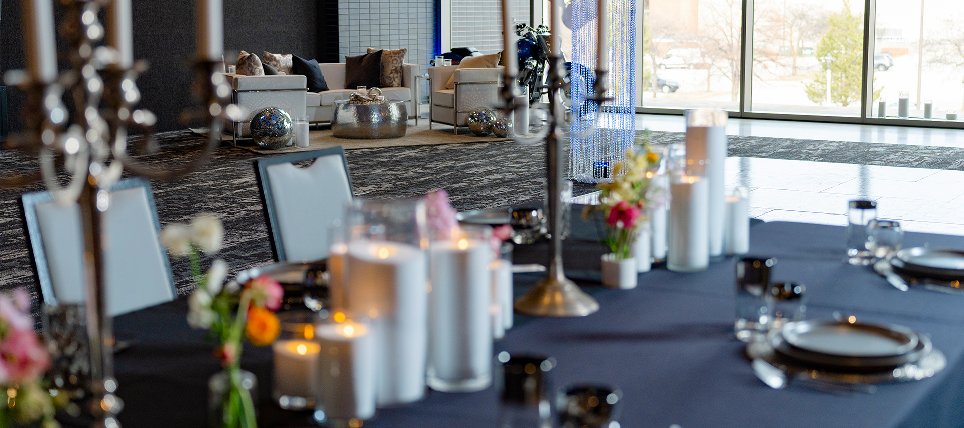 Dining table with candles, flowers, and place settings in event space