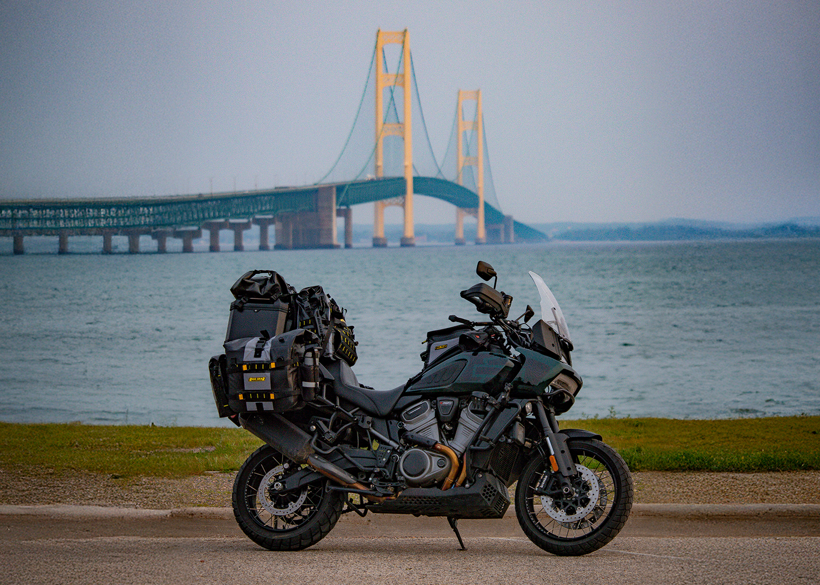 The author’s Harley-Davidson Pan America motorcycle parked by the water with the Mackinac Bridge rising in the background.
