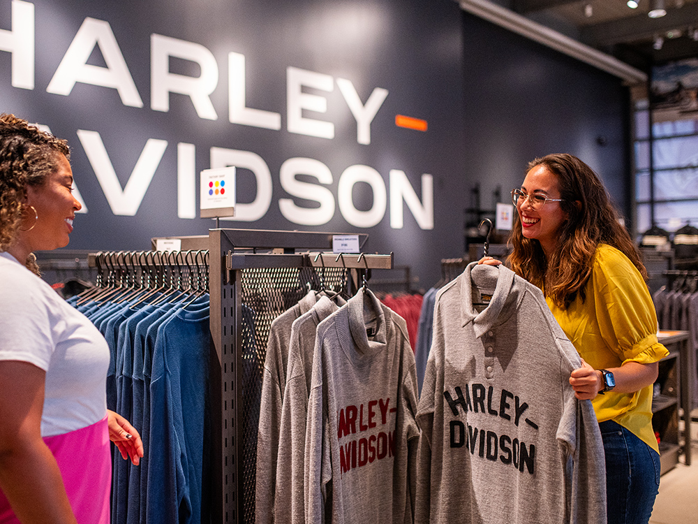 Customers selecting Harley-Davidson hoodies from retail clothing display
