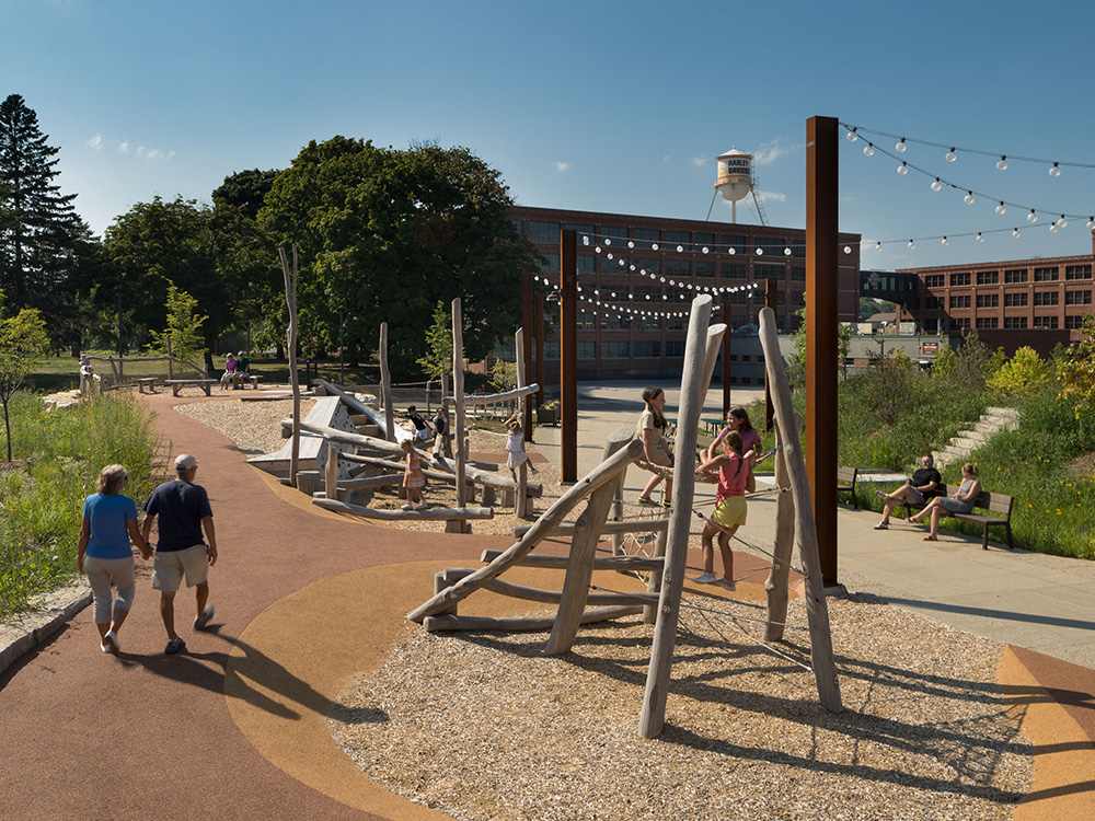 People at a park playground with climbing structures and seating