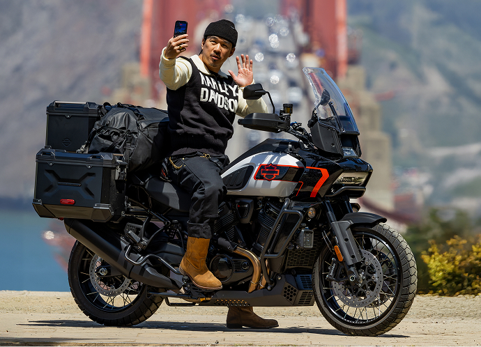 Motorcyclist sits on a Harley-Davidson Pan America 1250 Limited taking a selfie with the Golden Gate Bridge in the background