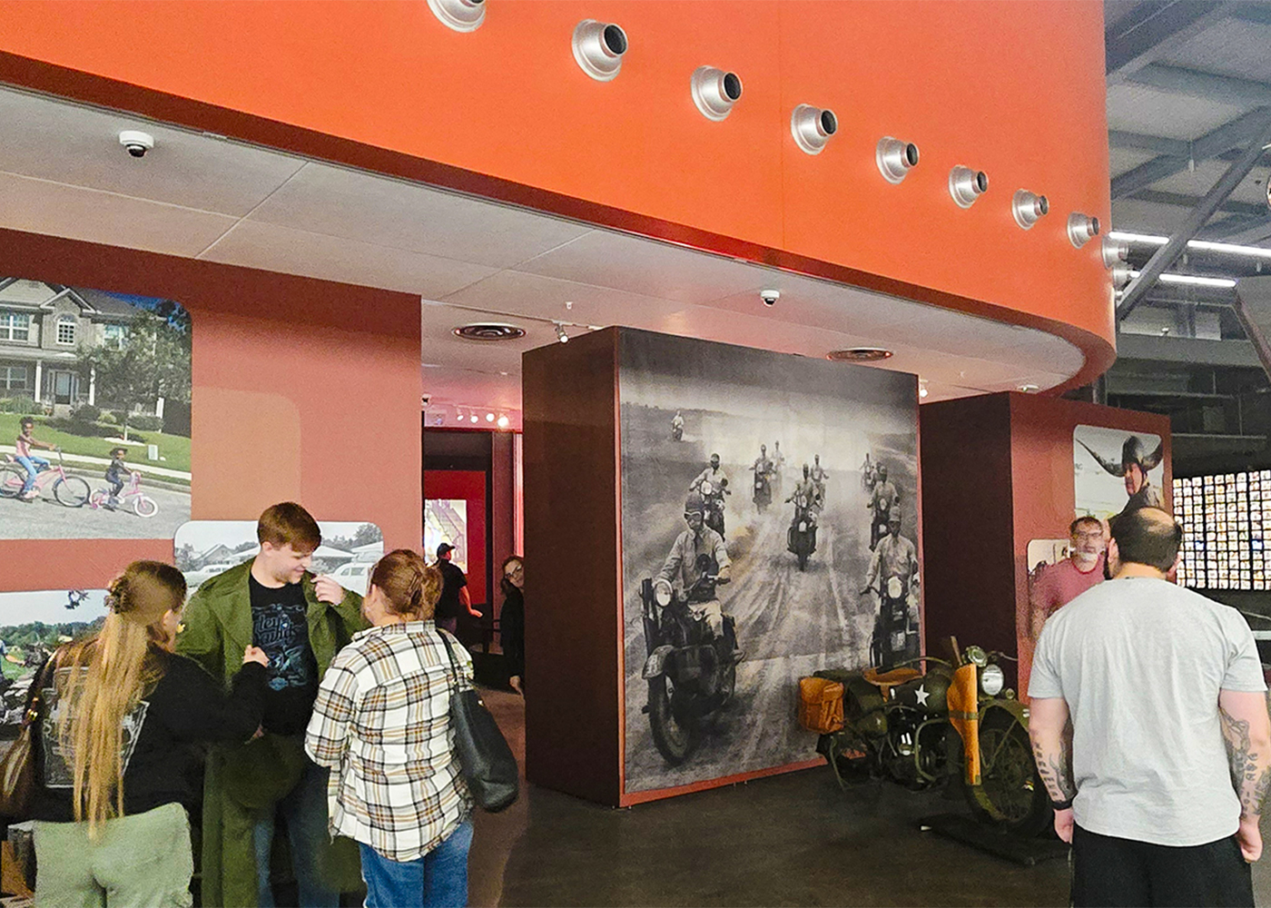 Visitors exploring Harley-Davidson museum exhibit with historic motorcycle displays