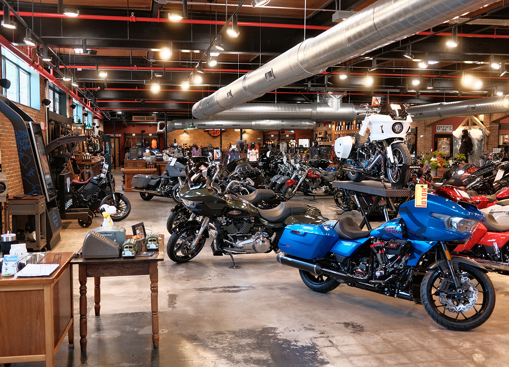 Interior of Harley-Davidson dealership with multiple touring motorcycles on display under industrial lighting