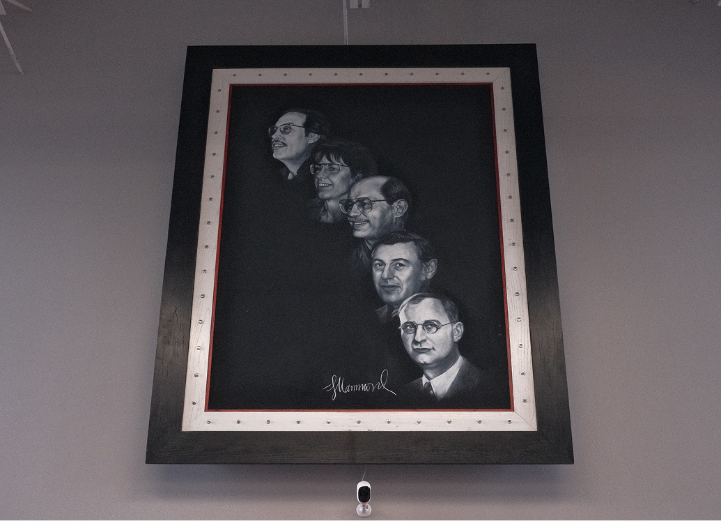 A painted family portrait hanging on a wall that traces 5 Kegel Harley-Davidson owners through the generations