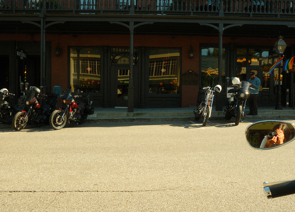 Motorcycles parked along a small-town street outside the historic National Exchange Hotel building with balconies and storefronts