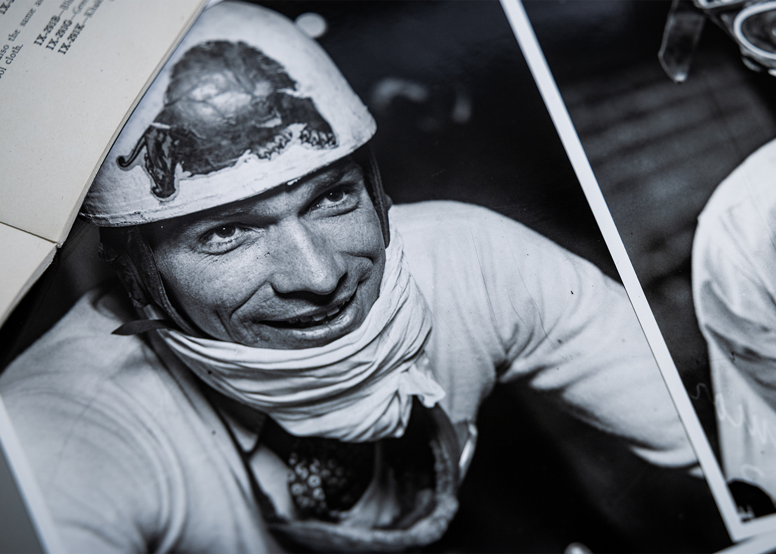 Photo of an archival black and white image of a smiling rider wearing a helmet with a lion insignia on the front.
