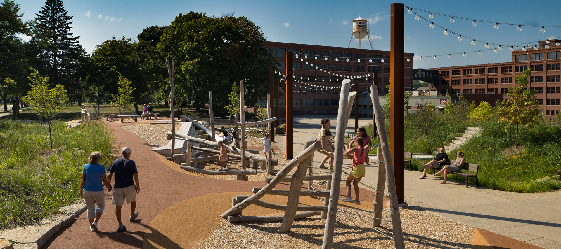 People at a park playground with climbing structures and seating