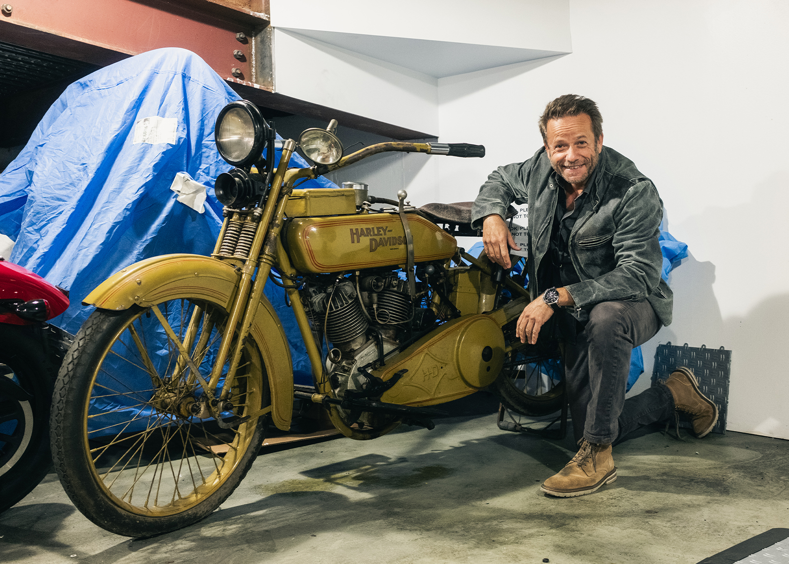 Larry Altholtz poses next to a restored early model Harley-Davidson.