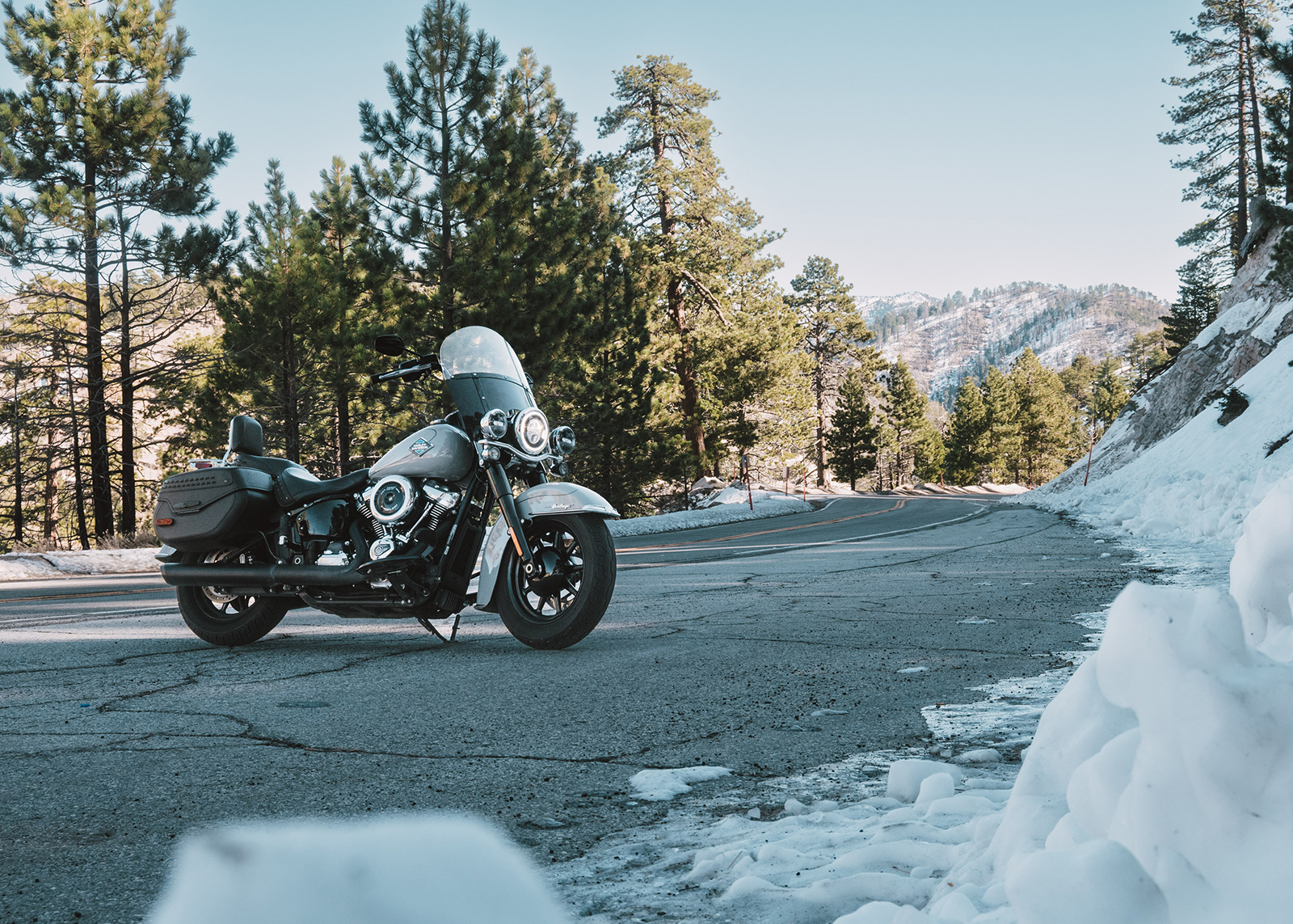 A Harley-Davidson Heritage Classic motorcycle parked roadside with plowed snow in the foreground