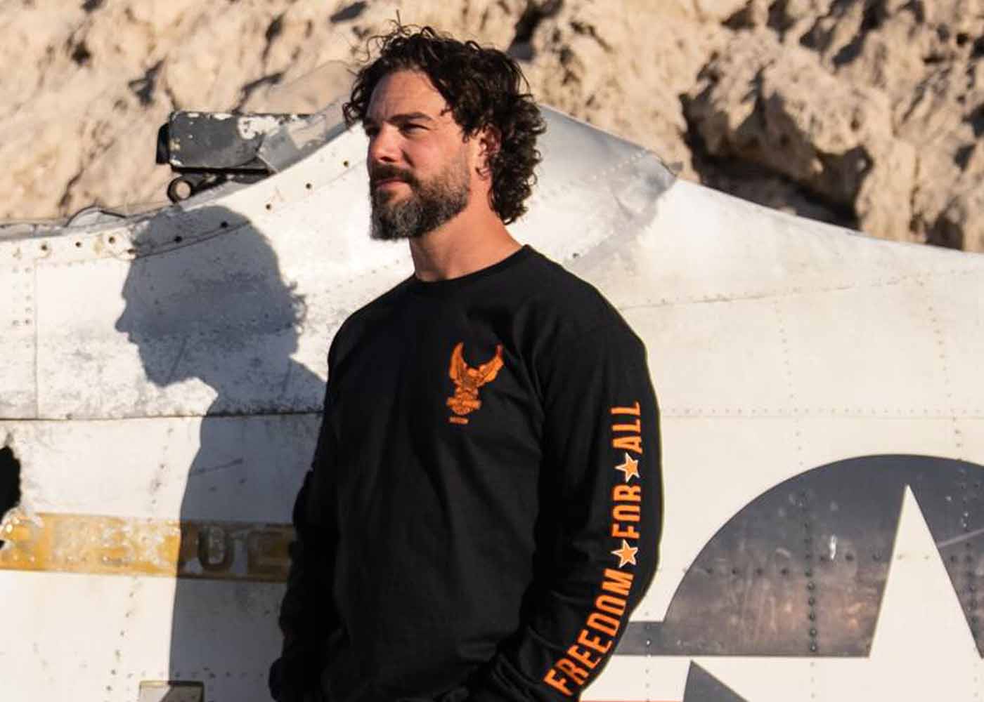 Man wearing long sleeve shirt next to airplane