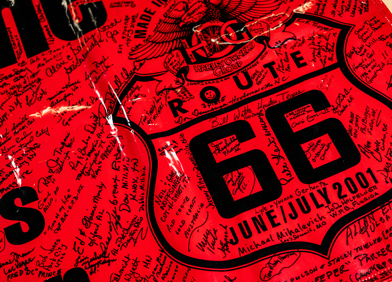 Bright red Harley Owners Group Route 66 2001 banner covered in handwritten signatures and messages