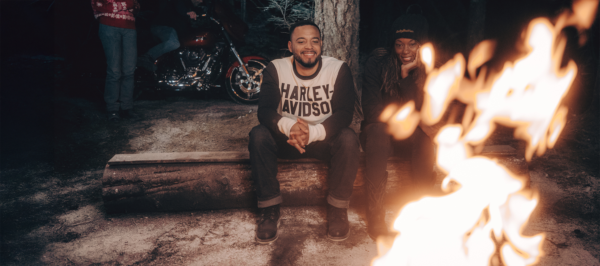 Man in Harley-Davidson shirt and woman sitting by a fire