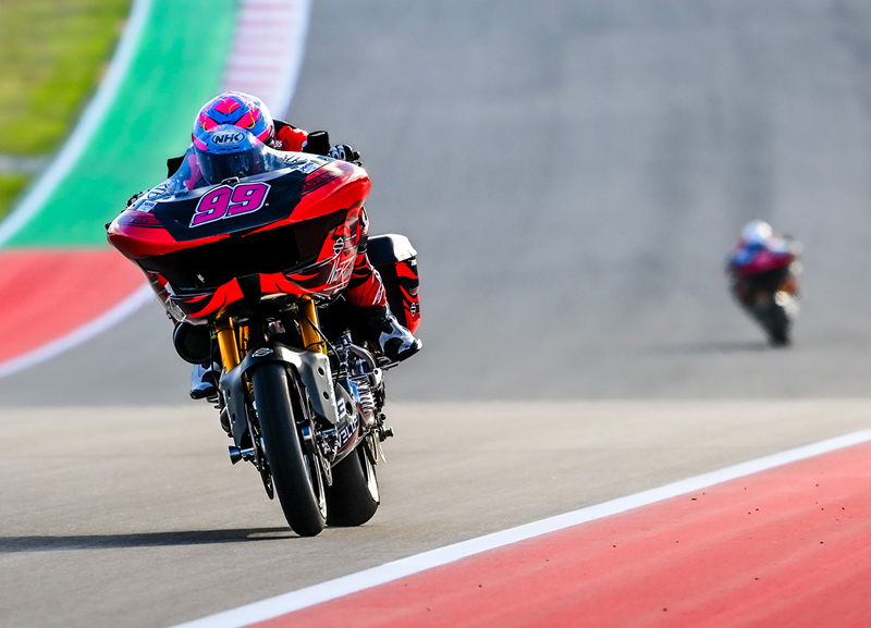 Motorcycle seen from the front at high speed on a straightaway with another rider visible in the distance