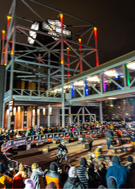 Large crowd gathers at the Harley-Davidson Museum at night while watching a mini bike flat track race