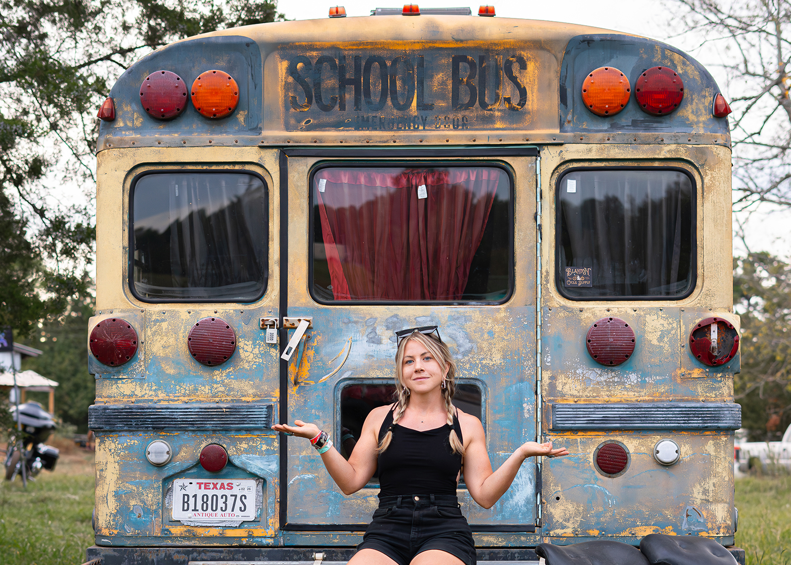 A woman sitting behind a rusted school bus