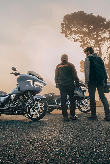 Motorcyclists stand next to bikes on side of road