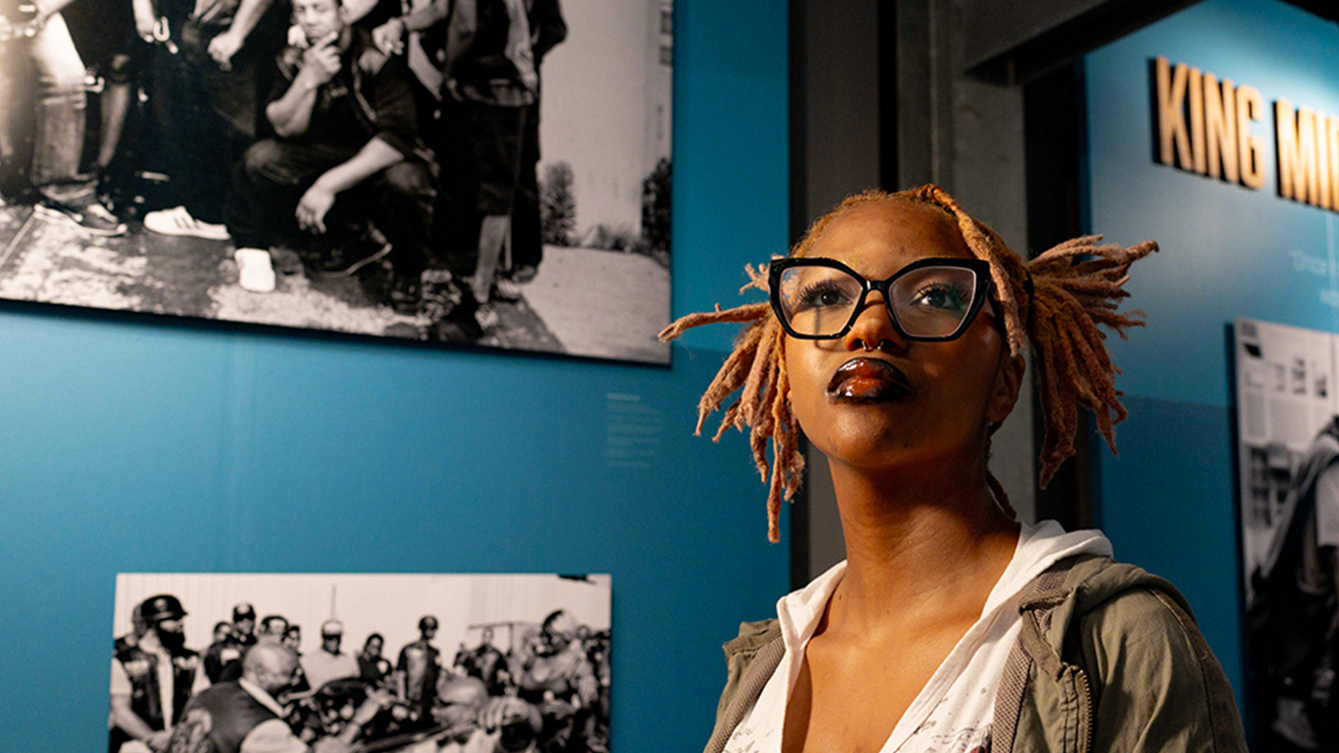 Person standing in museum gallery with historical photos on wall