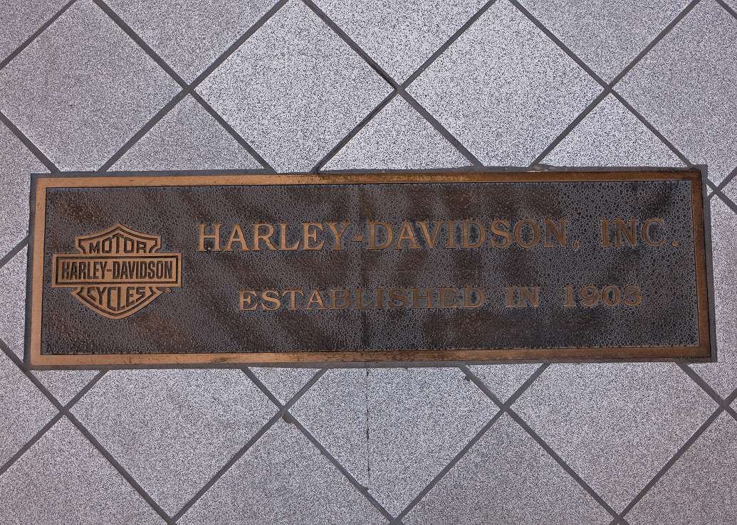 A plaque inlaid into a tile floor with the Harley-Davidson bar & Shield logo that says Harley-Davidson, INC. Established in 1903