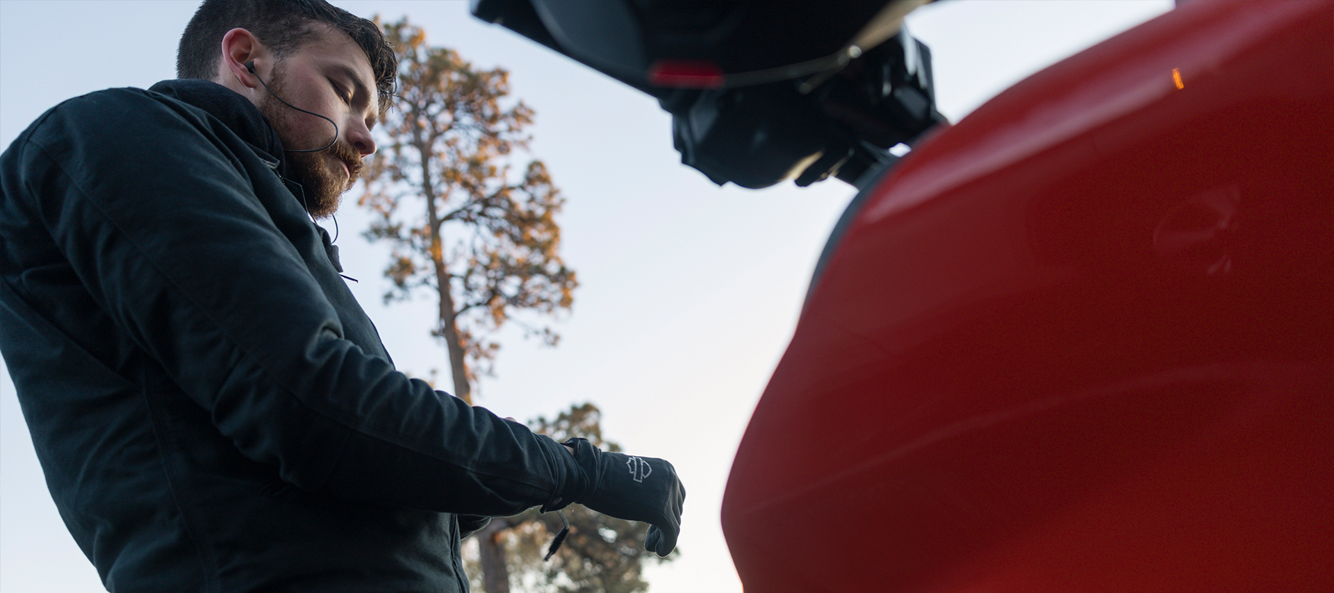 A motorcycle rider gears up with heated gloves and jacket before a ride