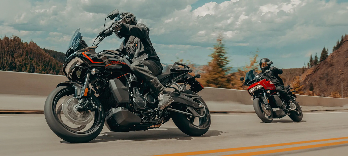Two Pan America STs lean through a turn on a mountain highway.