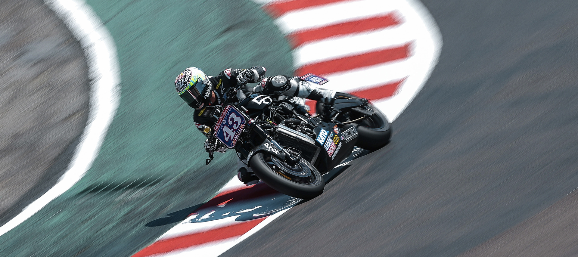 James Rispoli leans through The Corkscrew at Laguna Seca, skimming the red-white curbs.