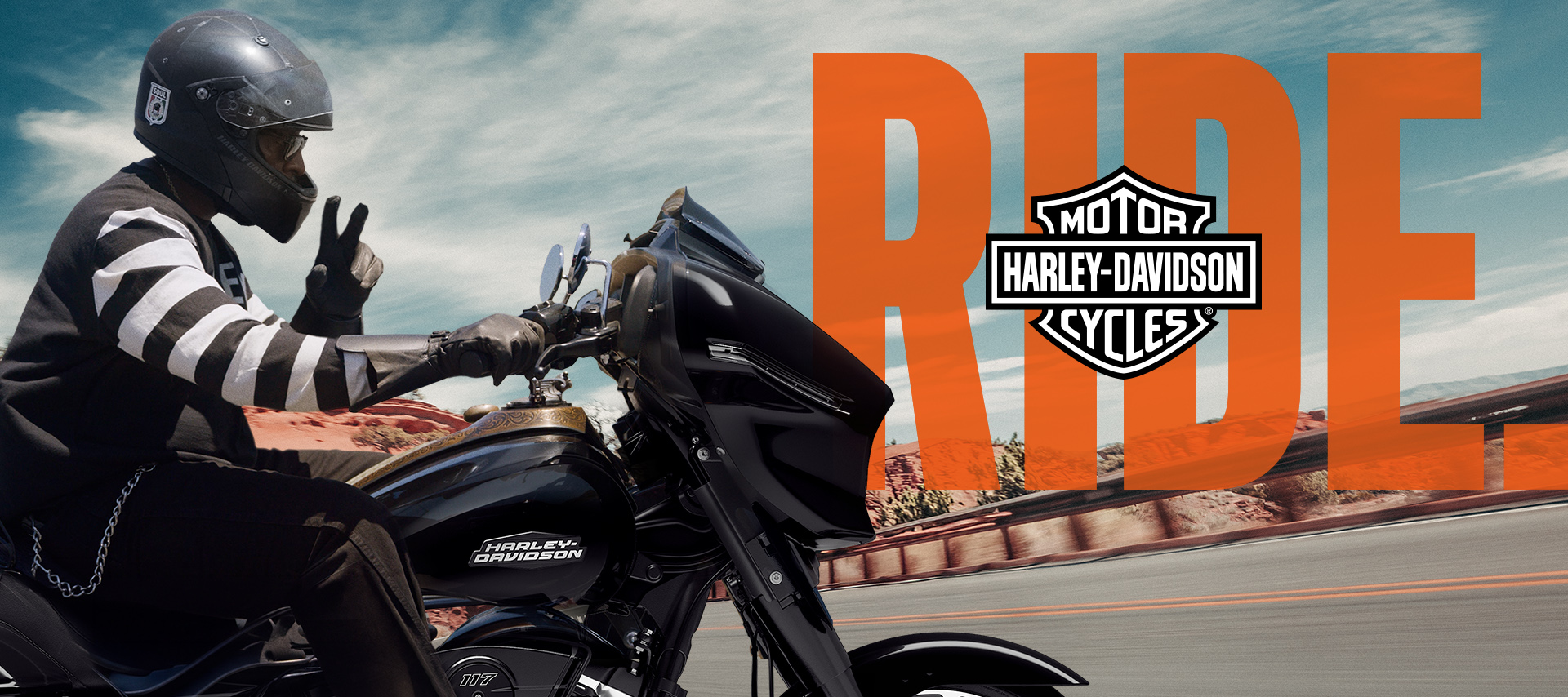 Motociclista fazendo o sinal da paz em uma Road Glide preta