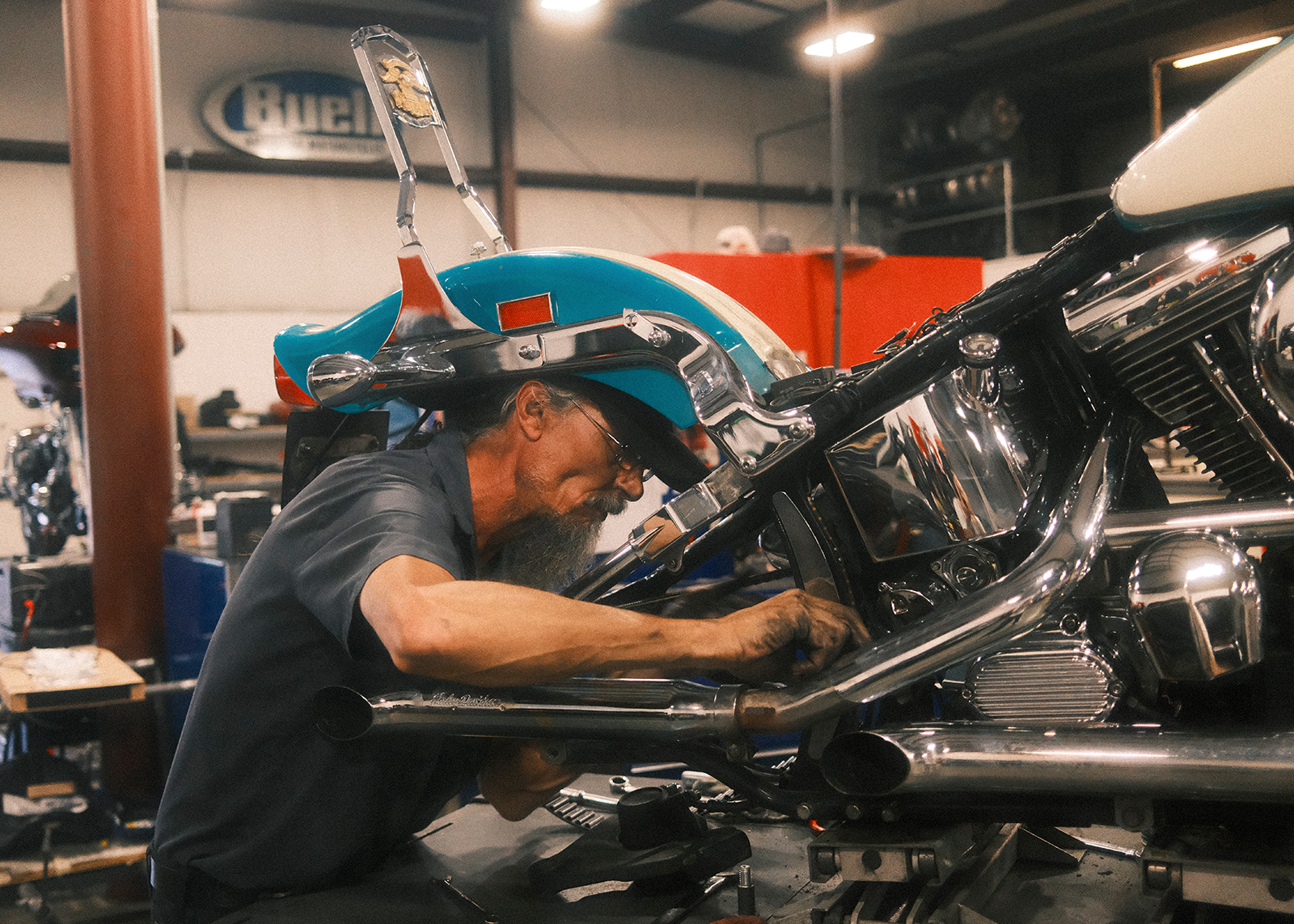 A Mechanic at Classic Harley-Davidson focuses intently while working on a motorcycle inside the service shop.
